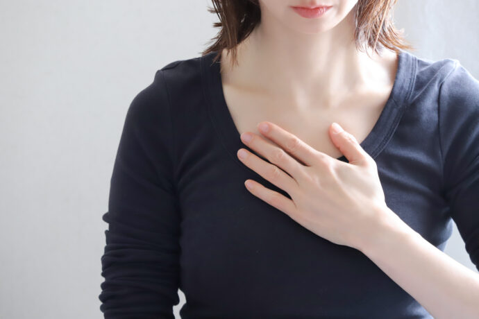 胸に手を当てて考える女性