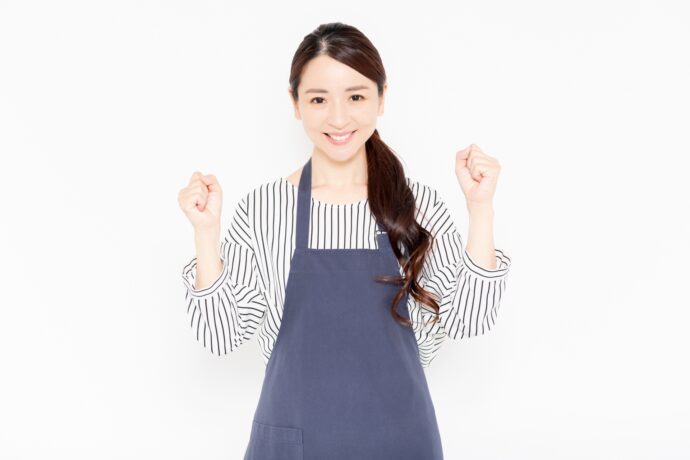 ガッツポーズをするエプロンを付けた女性